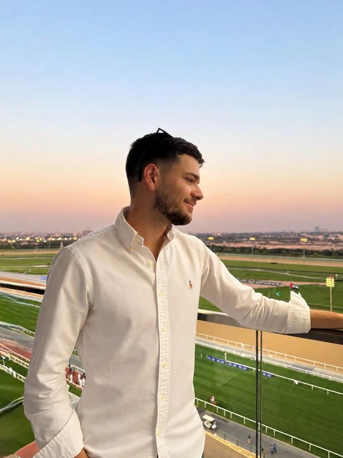 Alex Agius on a balcony overlooking a racecourse at sunset